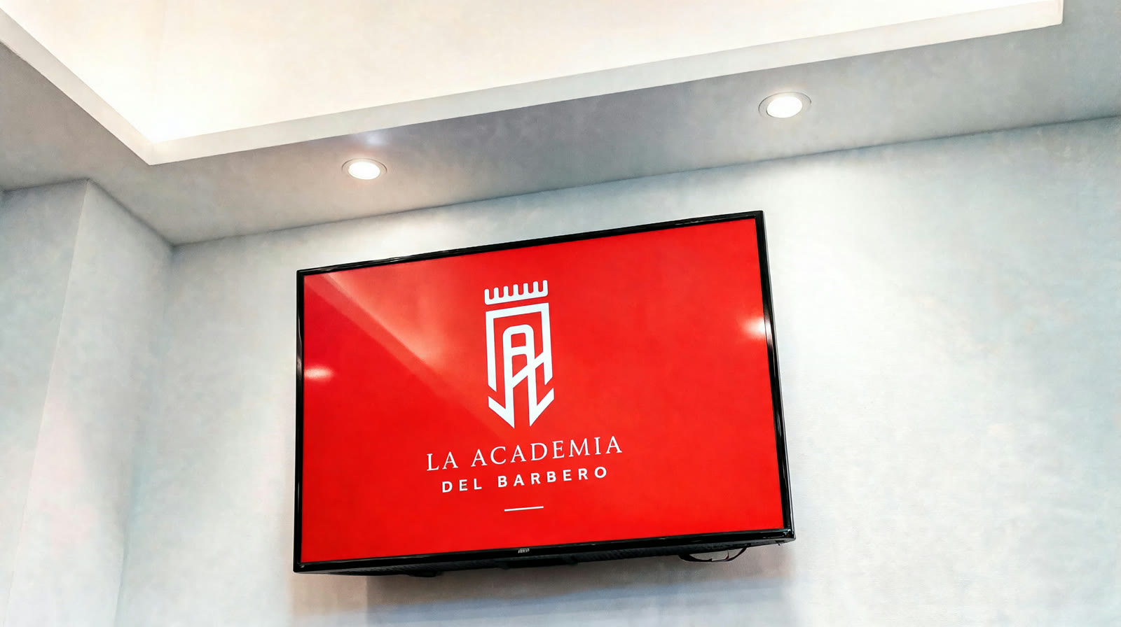TV del salón con el logo de la Academia del Barbero